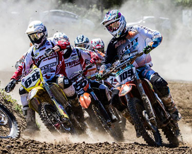 Pilotos lado a lado em curva na pista de terra de velocross